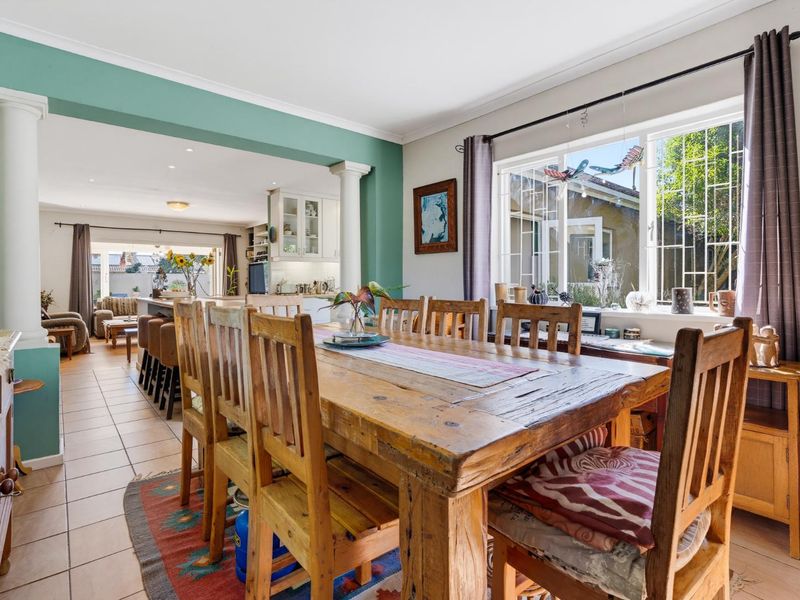 Spacious open-plan dining and kitchen area featuring tiled floors, decorative columns, and ample natural light through large windows.