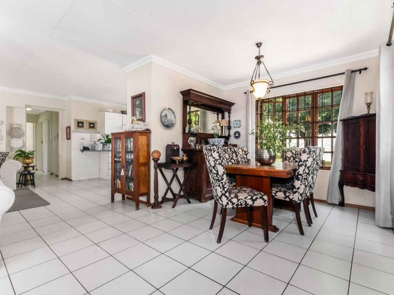 Spacious open-plan living and dining area featuring neutral tiled flooring, coved cornicing, and large timber-framed windows allowing for natural light.
