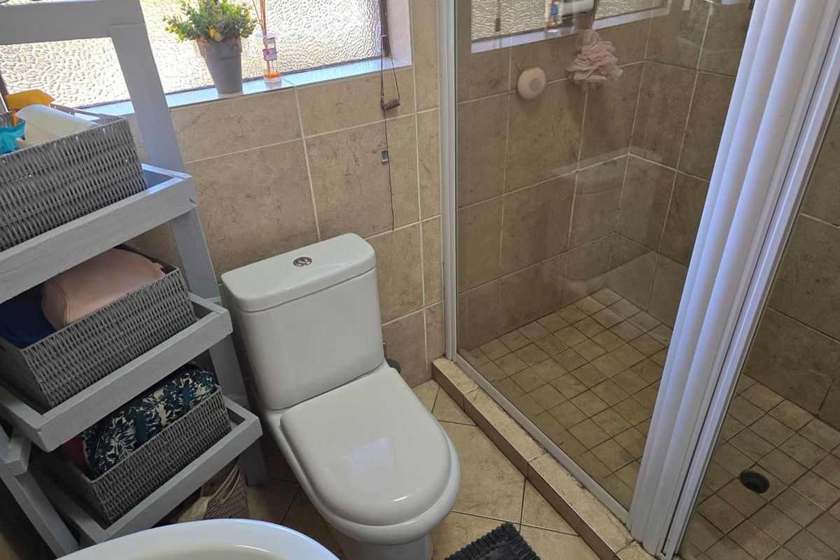 A functional bathroom featuring a glass-enclosed shower, a modern toilet, and neutral-toned wall and floor tiling.