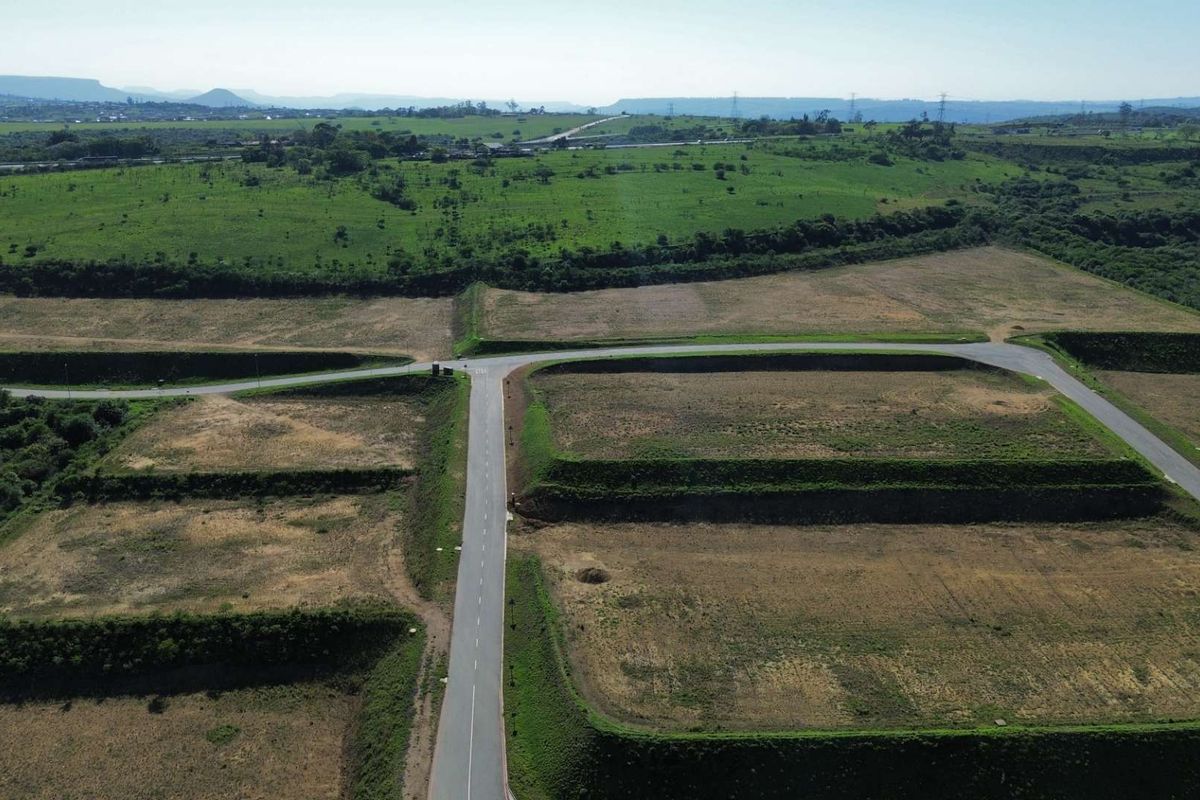 Aerial view of an industrial development site featuring paved access roads and prepared, terraced land plots ready for construction.
