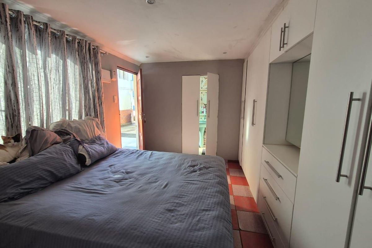 Bedroom featuring built-in cupboards, tiled flooring, and direct access to an outdoor area. The room requires cosmetic updates to improve its overall condition.