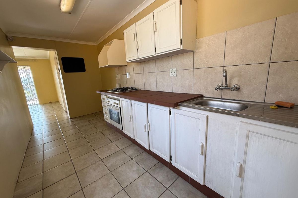 A functional kitchen featuring built-in cabinetry, a gas hob, an integrated oven, and tiled flooring, offering a blank canvas for potential modern updates.