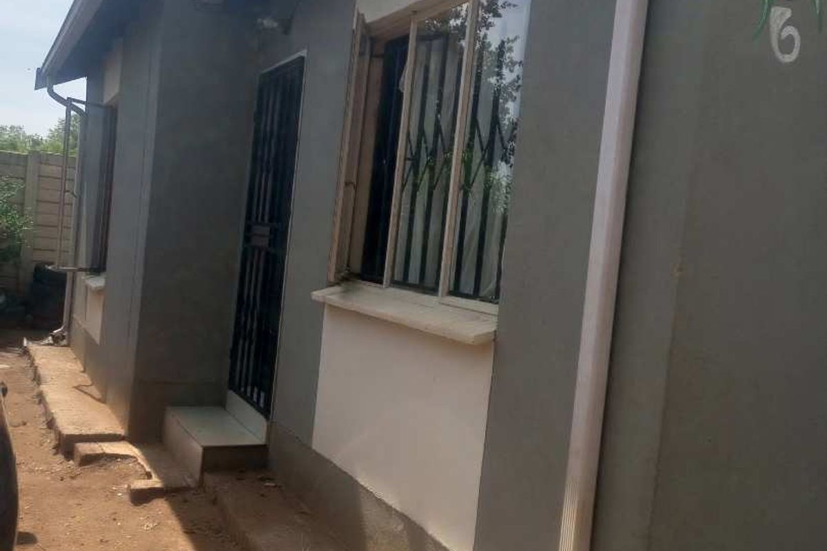 Side view of the property exterior featuring security gates, burglar bars, and a functional rainwater downpipe system.