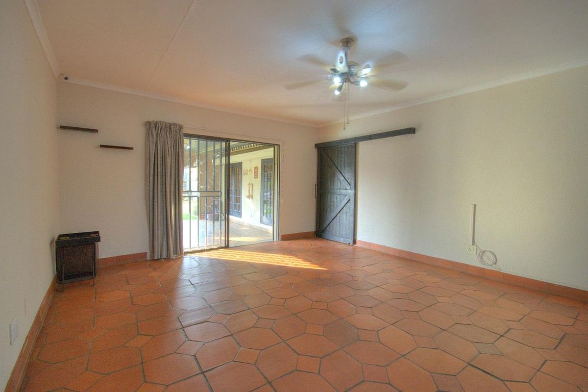 Spacious living area featuring terracotta tile flooring, a ceiling fan, and a sliding door providing access to the outdoor patio.