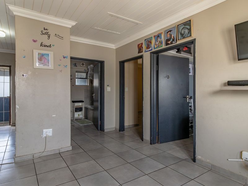 A functional hallway featuring tiled flooring, timber panelled ceilings, and access to multiple rooms within the apartment.