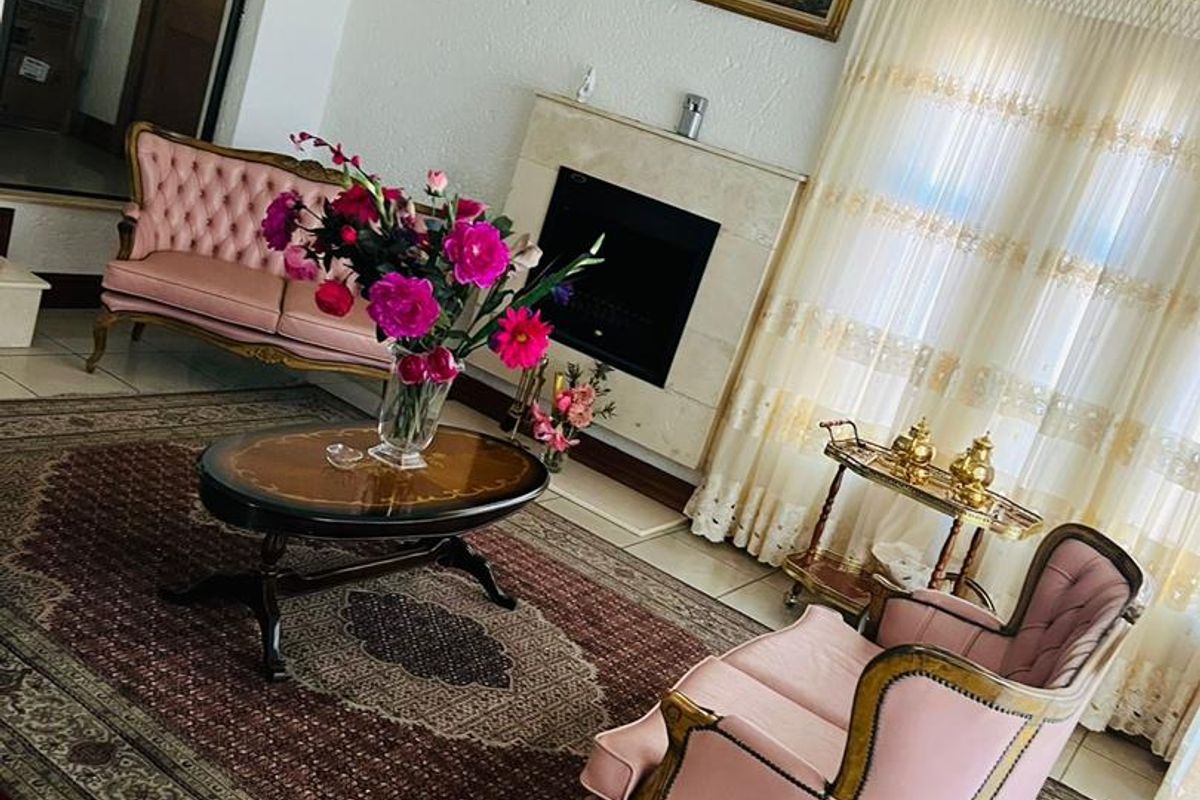 A formal living room featuring a built-in fireplace with a stone surround, crown molding, and tiled flooring.