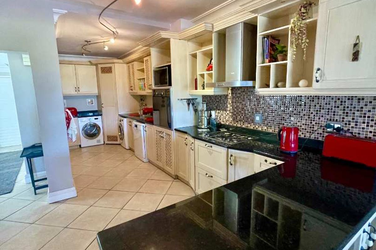 Spacious kitchen featuring granite countertops, built-in cabinetry, a gas hob, and integrated laundry facilities, offering a functional layout with ample storage space.