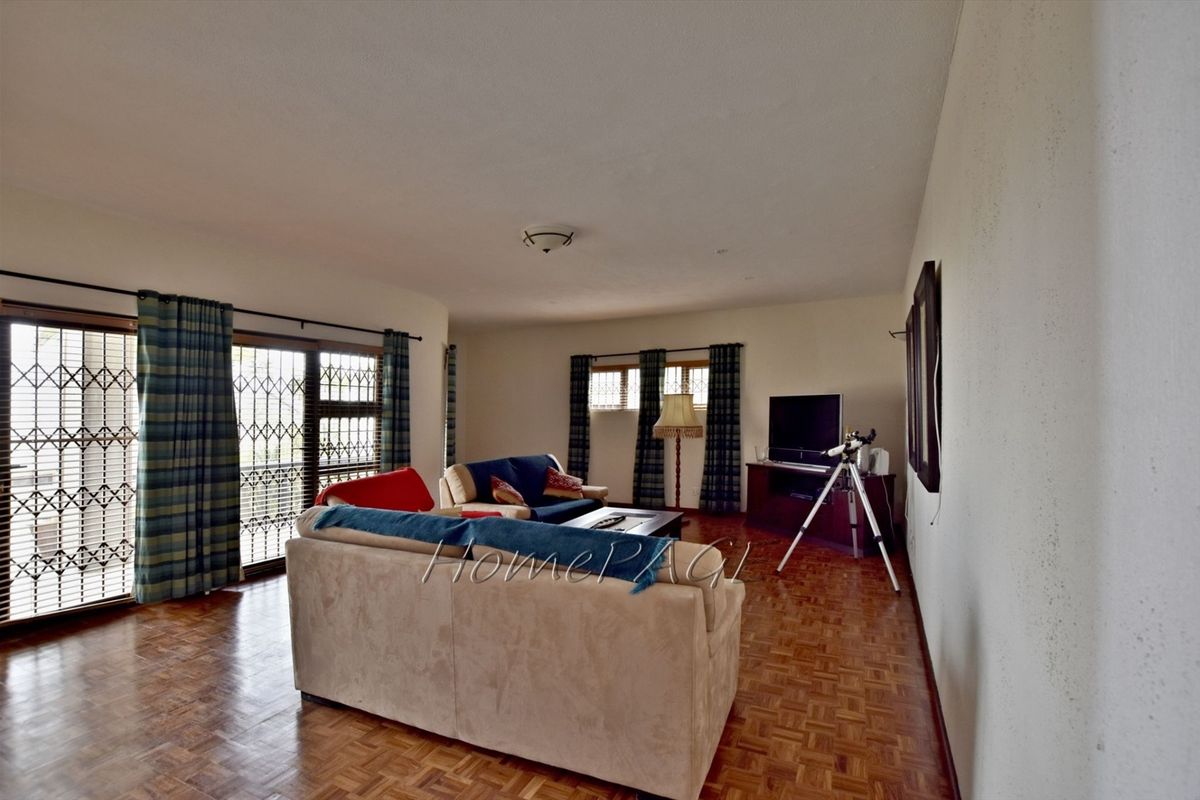 Spacious living room featuring traditional parquet flooring, large sliding glass doors with security gates, and ample natural light.