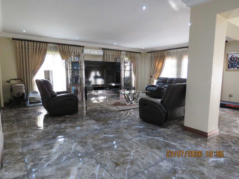 Spacious living room featuring polished marble-look floor tiles, recessed downlighting, and a wall-mounted split-system air conditioner.