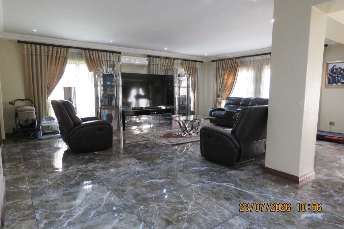 Spacious living room featuring polished marble-look floor tiles, recessed downlighting, and a wall-mounted split-system air conditioner.