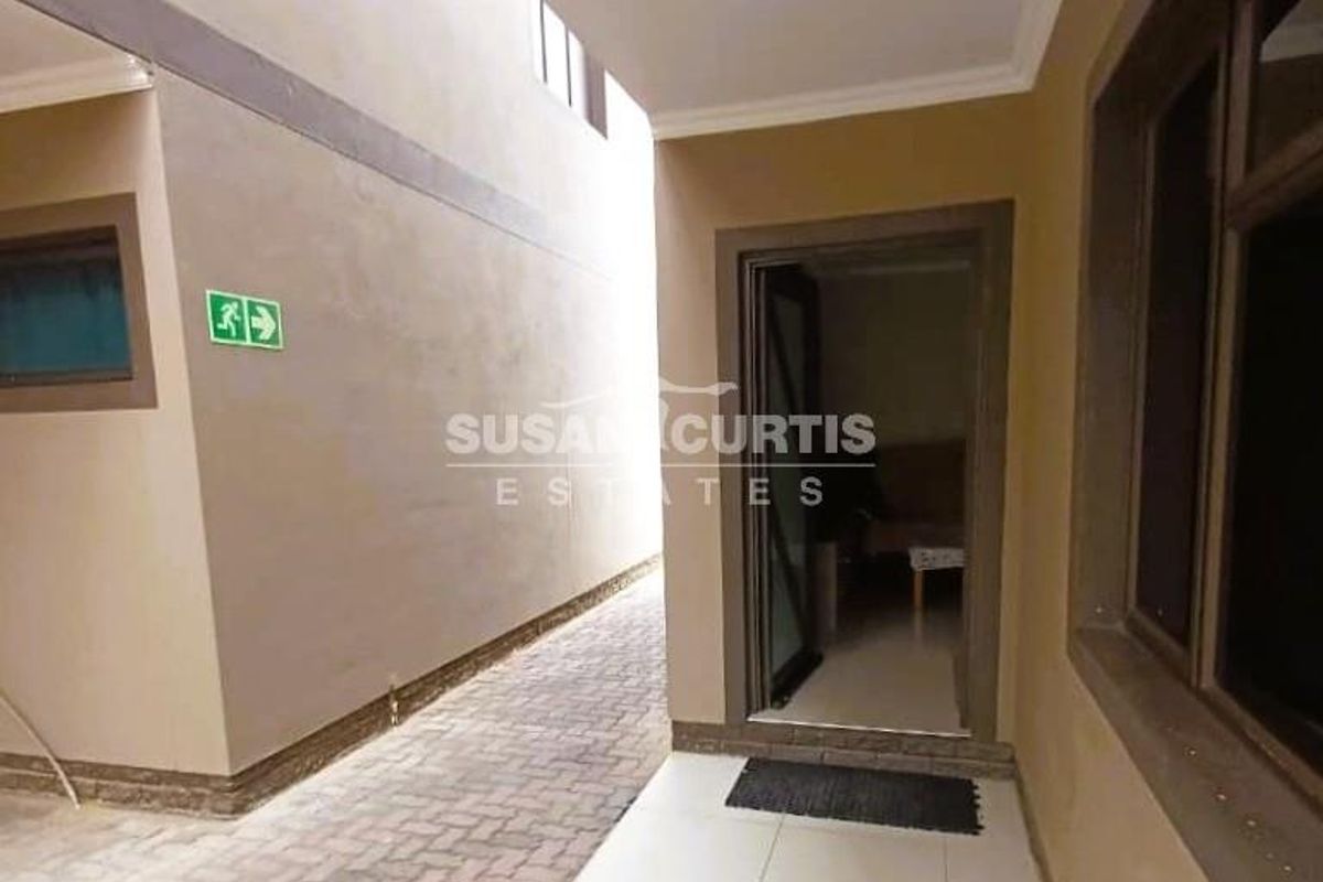 A view of a paved side walkway leading to an entrance, featuring clean exterior walls and tiled flooring at the doorway.