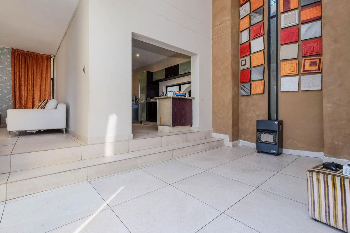 A split-level living area featuring tiled flooring, a raised platform leading to the kitchen, and a decorative feature wall.