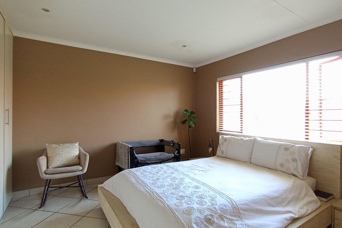 A well-lit bedroom featuring neutral-toned walls, tiled flooring, and built-in cupboards, offering a functional and comfortable living space.