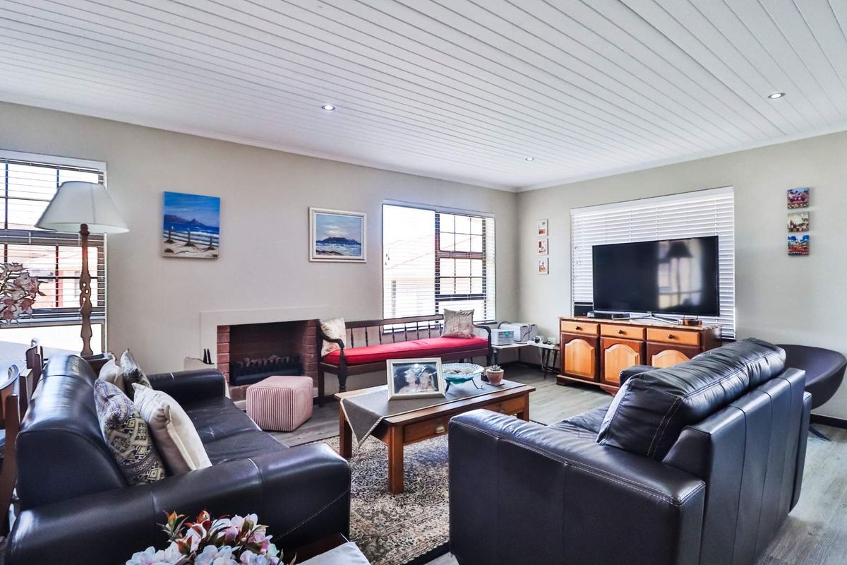 A comfortable living room featuring a built-in fireplace, recessed ceiling lighting, and large windows with venetian blinds, offering a functional and inviting space.