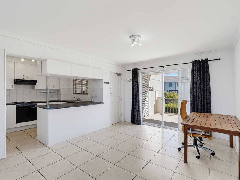 Open-plan living and kitchen area featuring tiled flooring, built-in cabinetry, and sliding glass doors leading to a private balcony.