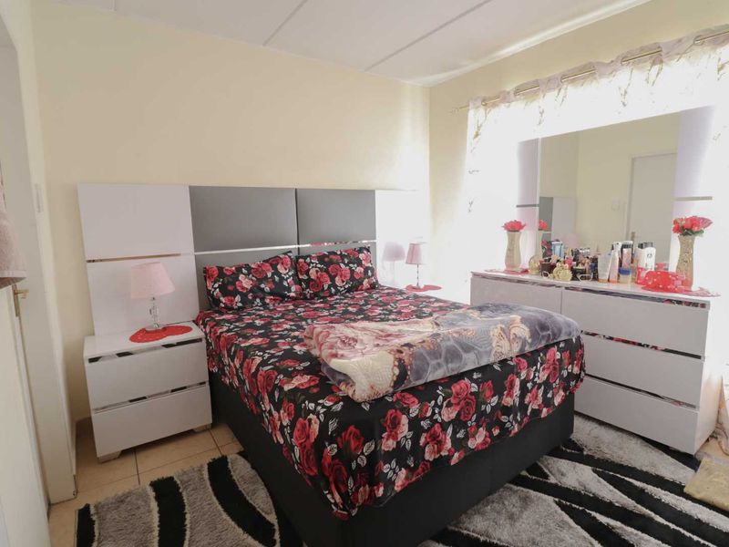 A well-lit bedroom featuring tiled flooring and a modern built-in headboard, offering a functional and comfortable living space.