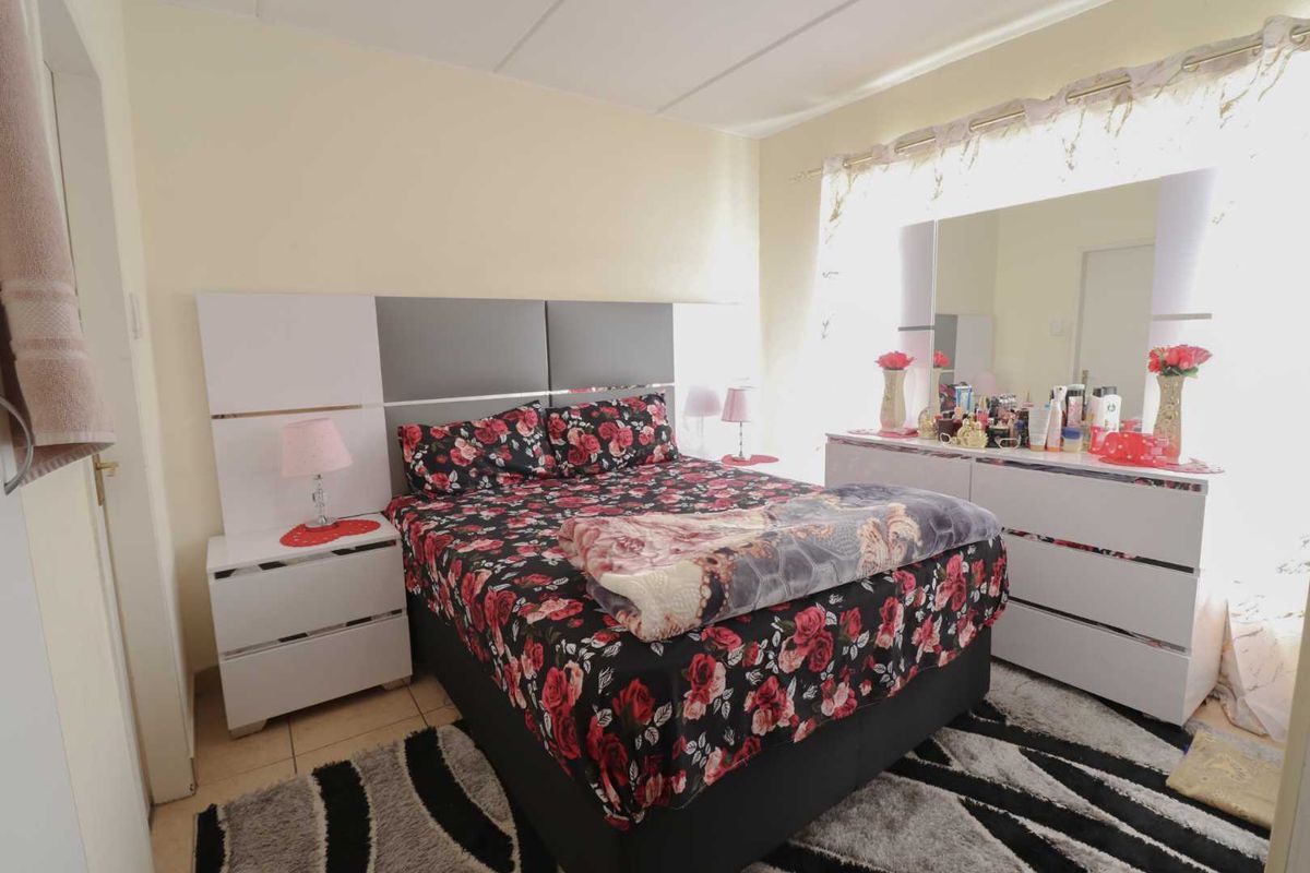 A well-lit bedroom featuring tiled flooring and a modern built-in headboard, offering a functional and comfortable living space.