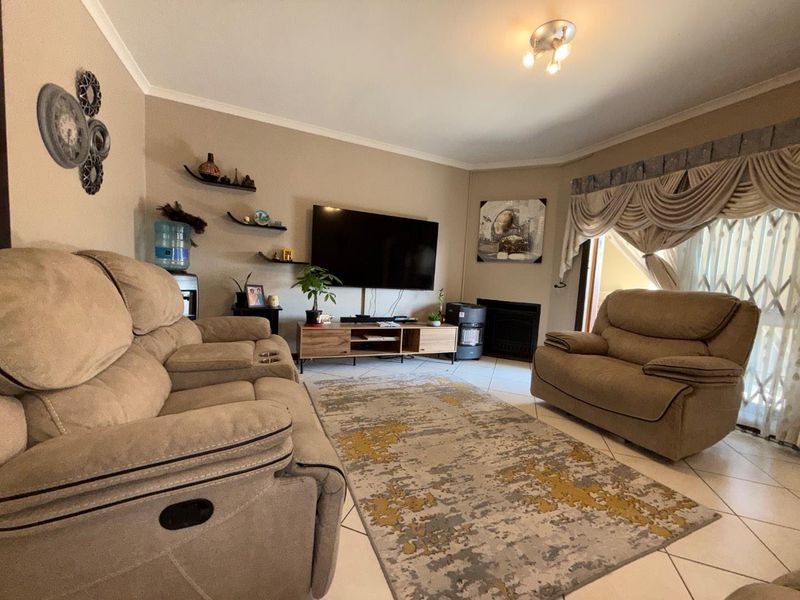 A comfortable living room featuring tiled flooring, a built-in fireplace, and access to an outdoor area through a security gate.