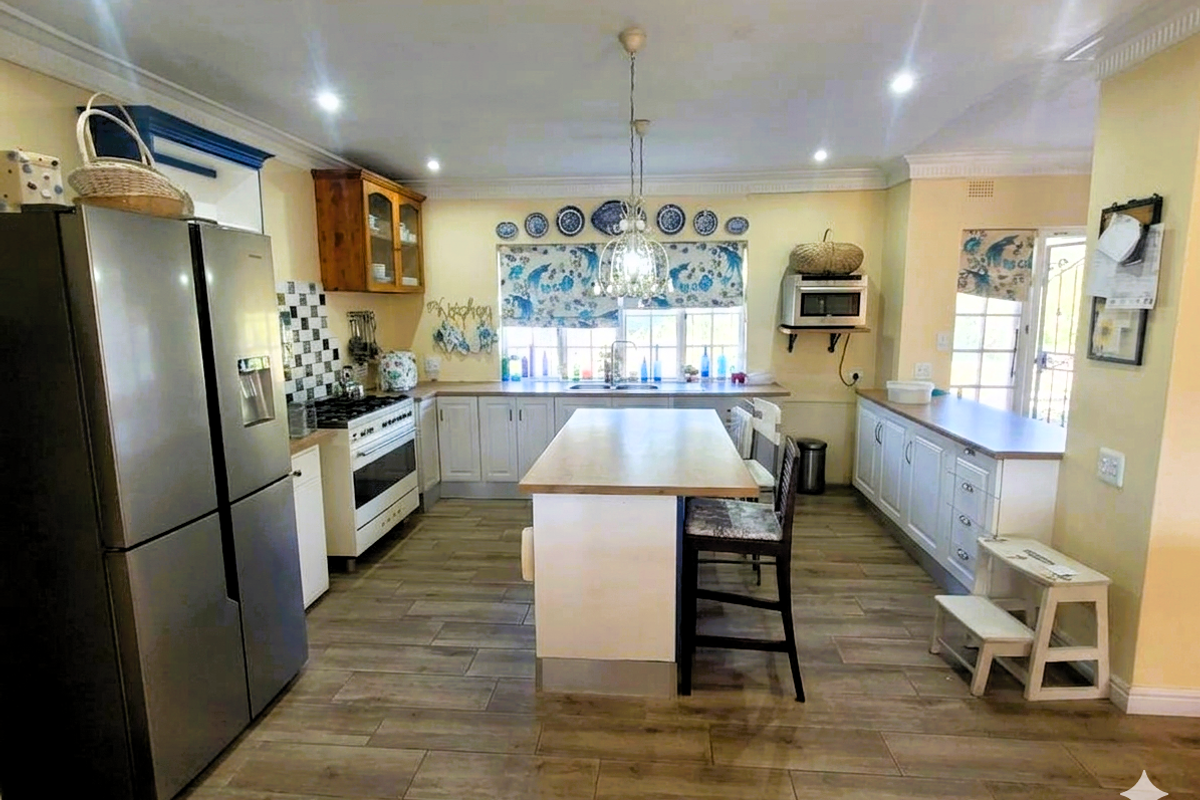 Spacious kitchen featuring a central island, wood-look tile flooring, built-in cabinetry, and a freestanding gas stove with extractor fan.