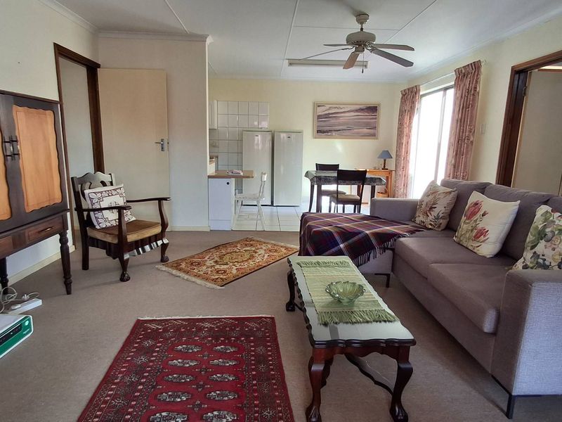 Open-plan living and dining area featuring a ceiling fan, carpeted flooring, and direct access to an outdoor space through sliding glass doors.