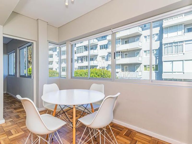 Bright dining area featuring classic parquet flooring and large sliding aluminium windows that provide ample natural light and an urban outlook.