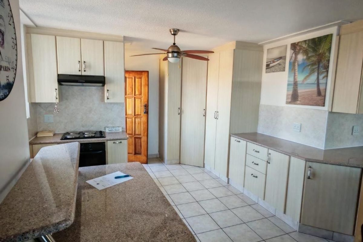 A functional kitchen featuring light-toned built-in cabinetry, granite countertops, a gas hob, and tiled flooring with a breakfast nook area.
