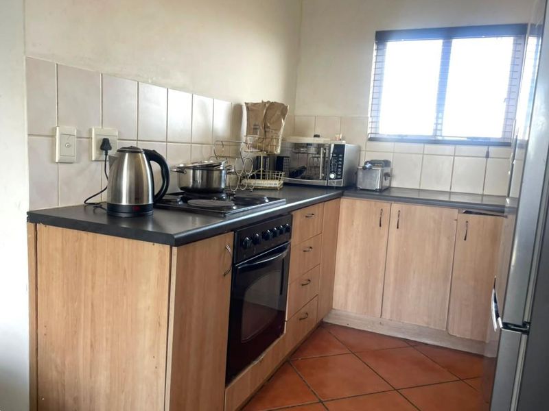 A functional kitchen featuring laminate cabinetry, built-in oven, hob, tiled backsplash, and durable tiled flooring, offering a practical layout for daily meal preparation.