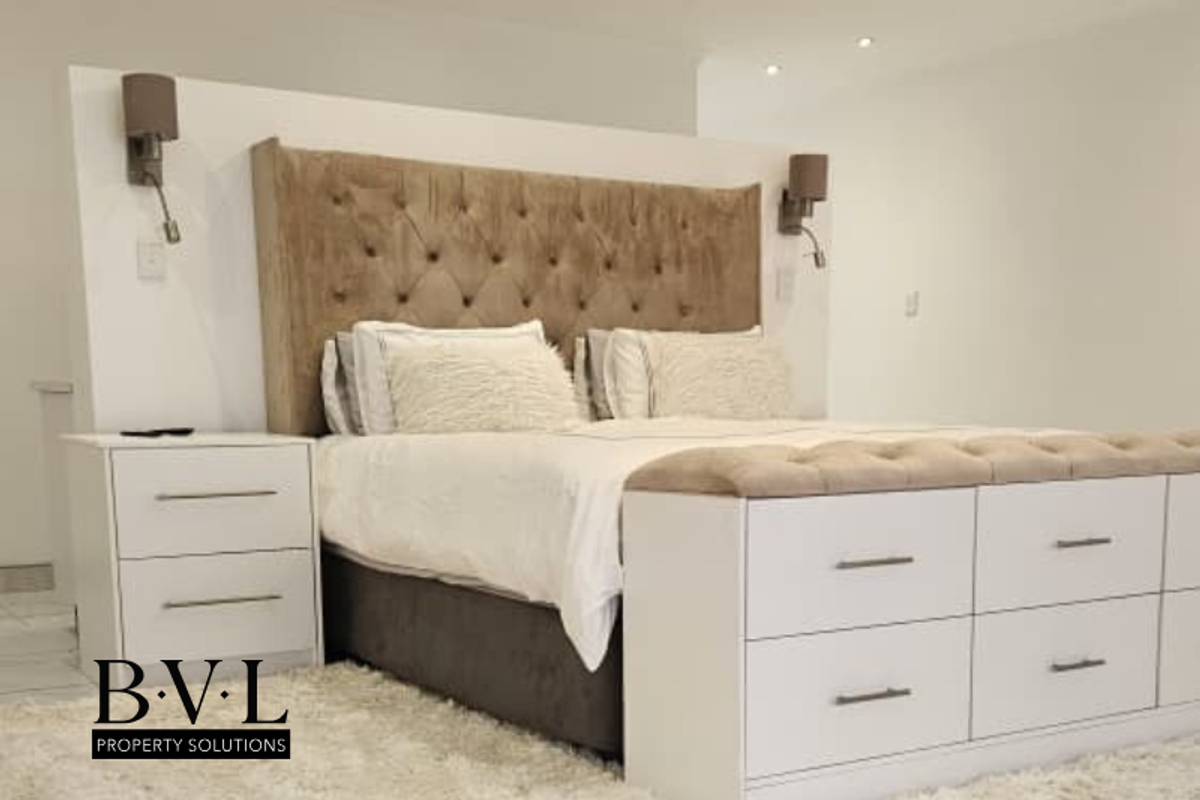 A well-appointed bedroom featuring a custom built-in headboard partition with integrated wall-mounted lighting and matching built-in storage units.