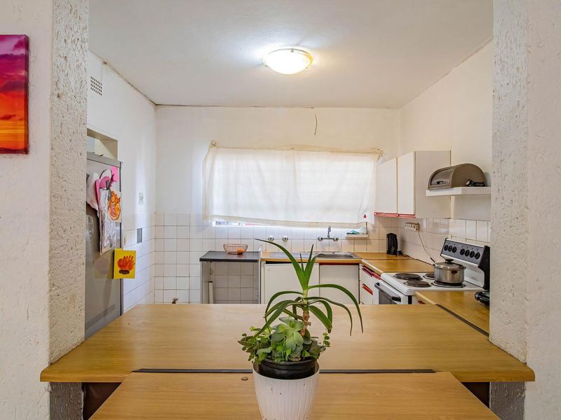 A functional kitchen featuring built-in cabinetry, a tiled splashback, and a breakfast bar opening into the living area.