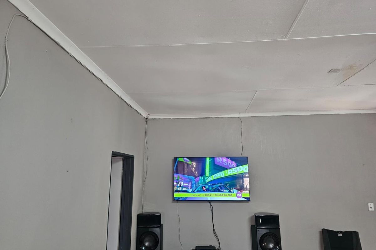 A living room area featuring grey painted walls and standard ceiling finishes, currently used as a media space.