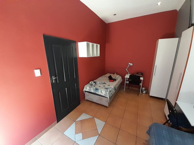 A bedroom featuring red painted walls, tiled flooring with a decorative inlay, and recessed ceiling lighting.