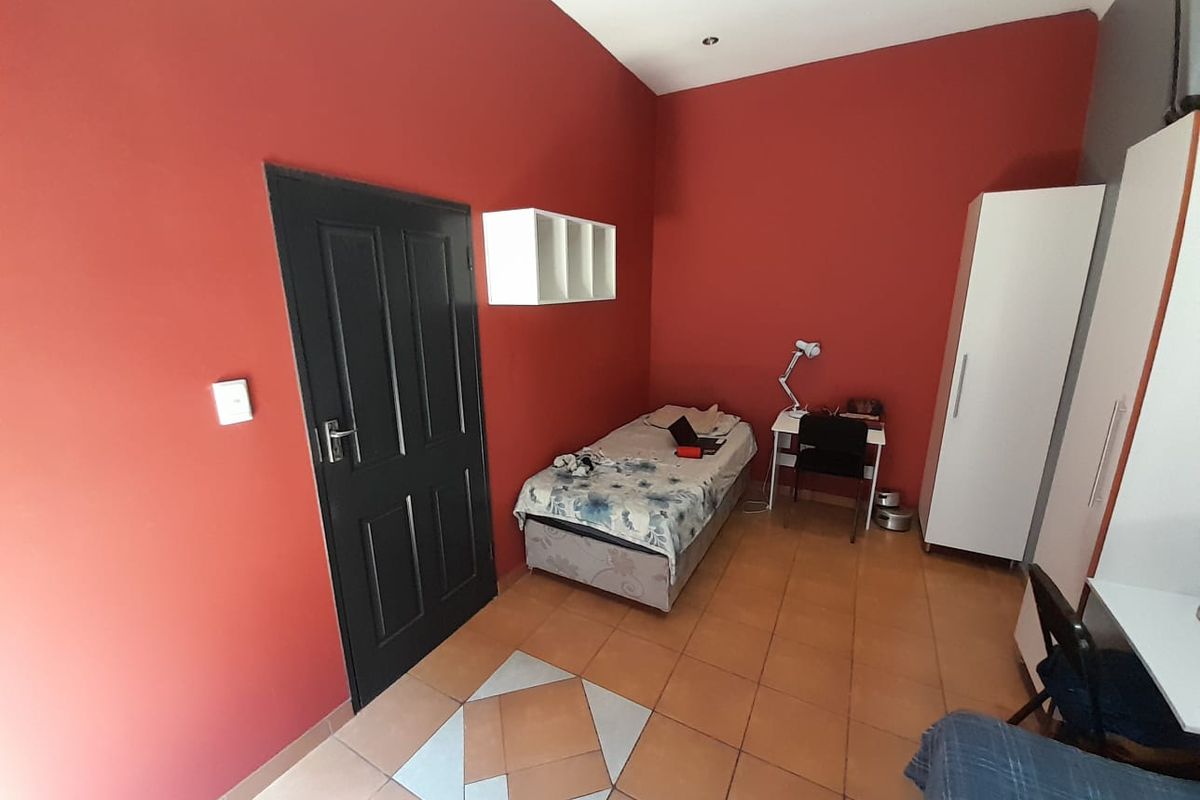 A bedroom featuring red painted walls, tiled flooring with a decorative inlay, and recessed ceiling lighting.