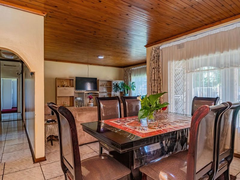 Dining area featuring tiled flooring, a timber tongue and groove ceiling, and an arched entryway leading to the hallway.