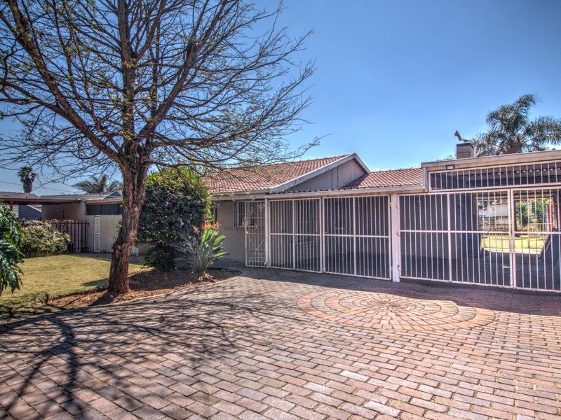 Front exterior view of the property featuring a brick paved driveway, secure gated entrance, and a tiled roof structure.