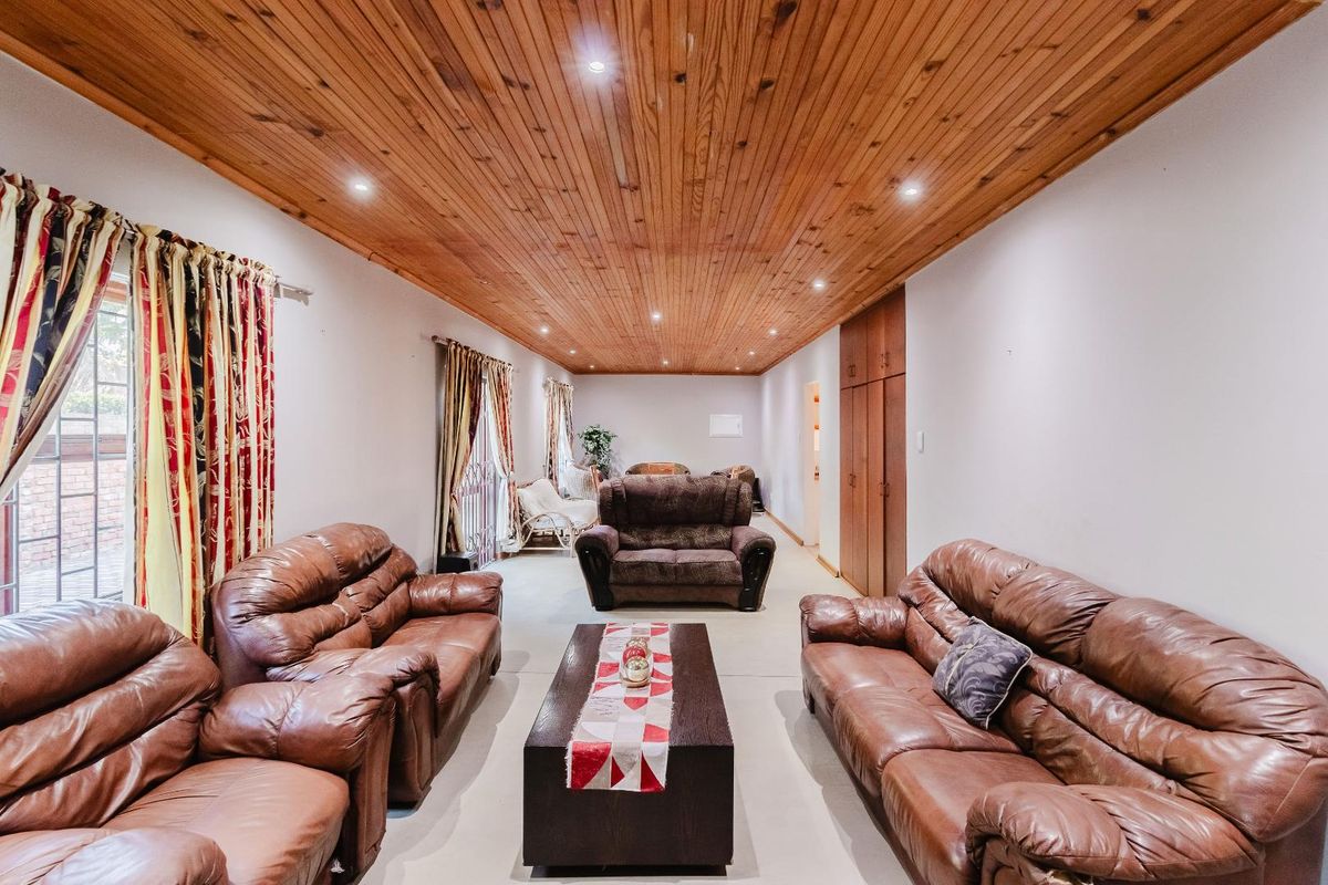 Spacious living room featuring a warm timber-clad ceiling with recessed downlighting and built-in storage cupboards.