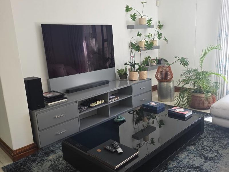 A well-maintained living room featuring neutral walls, tiled flooring, recessed downlighting, and custom built-in cabinetry for media storage.