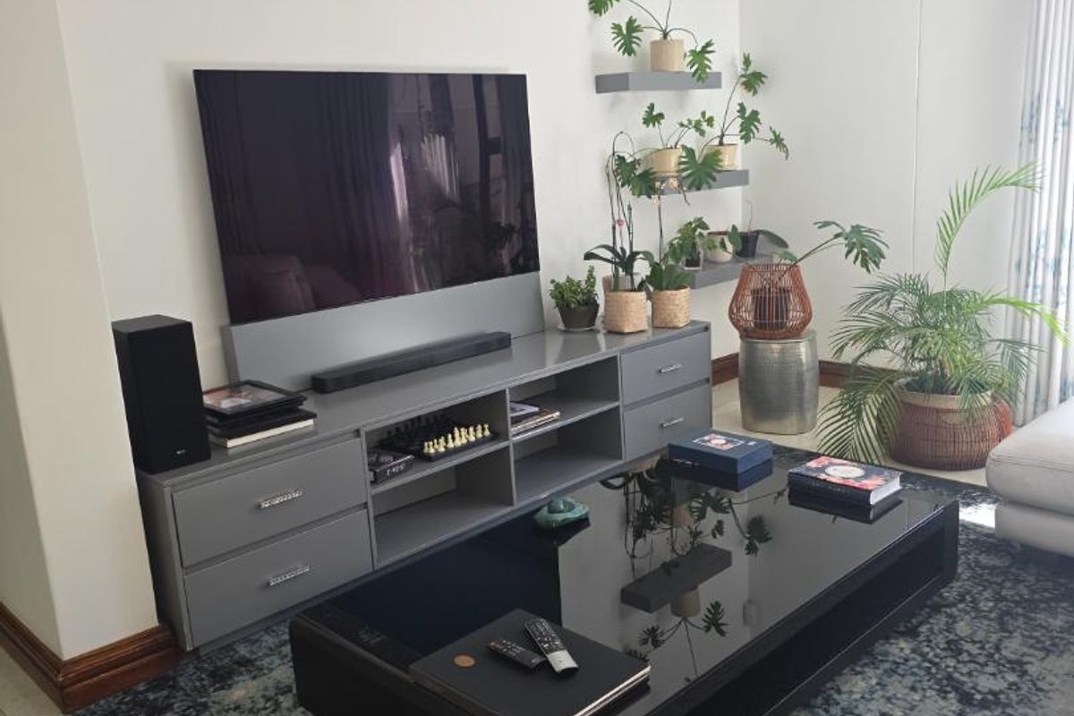 A well-maintained living room featuring neutral walls, tiled flooring, recessed downlighting, and custom built-in cabinetry for media storage.