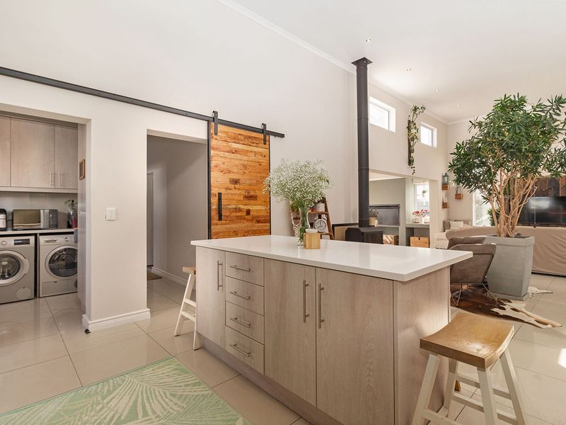 Spacious open-plan living area featuring a modern kitchen island, sleek cabinetry, a striking sliding barn door, and a contemporary freestanding fireplace.