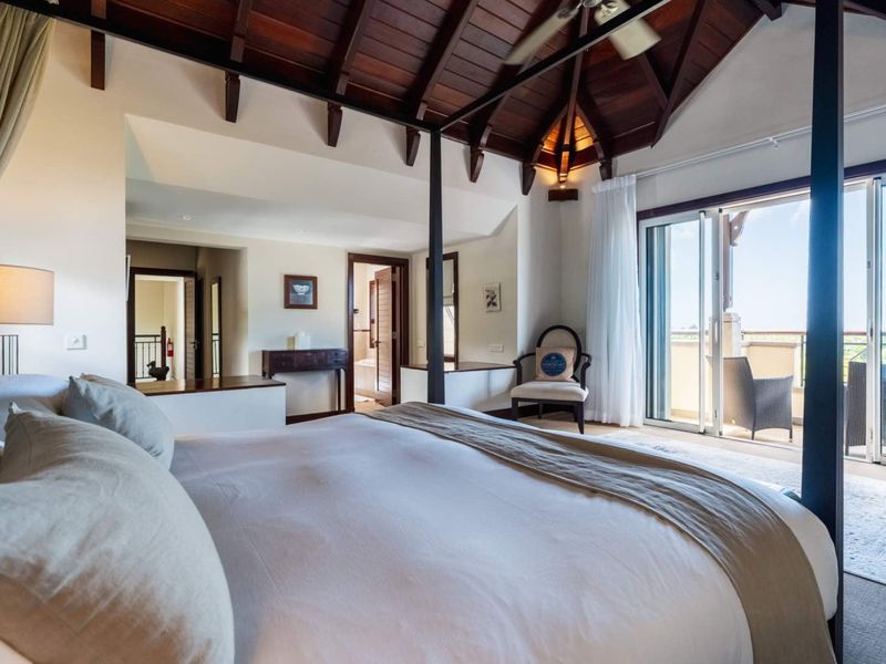 Spacious bedroom featuring a vaulted timber ceiling, exposed beams, and sliding glass doors opening onto a private balcony.