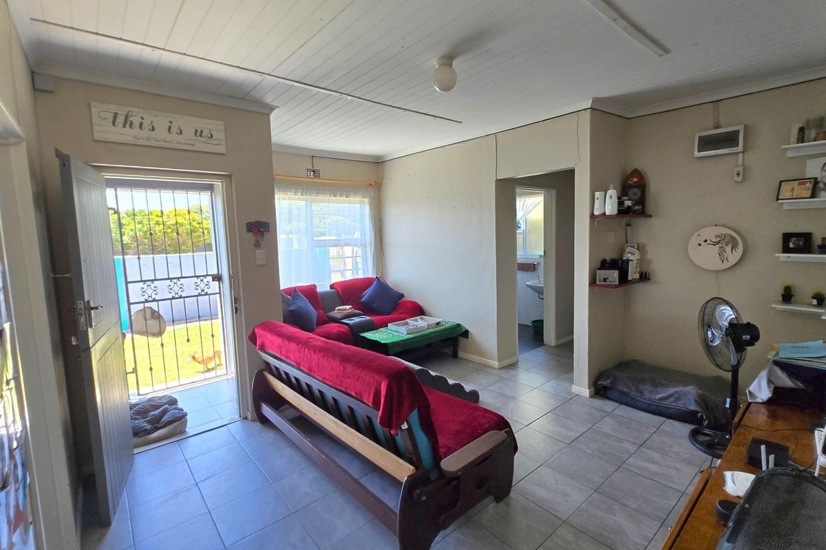 A functional living room featuring tiled flooring, a security gate entrance, and direct access to an adjacent bathroom area.