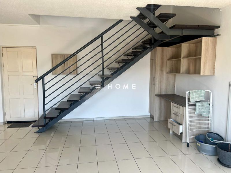 Open plan living area featuring a modern metal staircase and built-in study nook with integrated cabinetry and tiled flooring throughout.