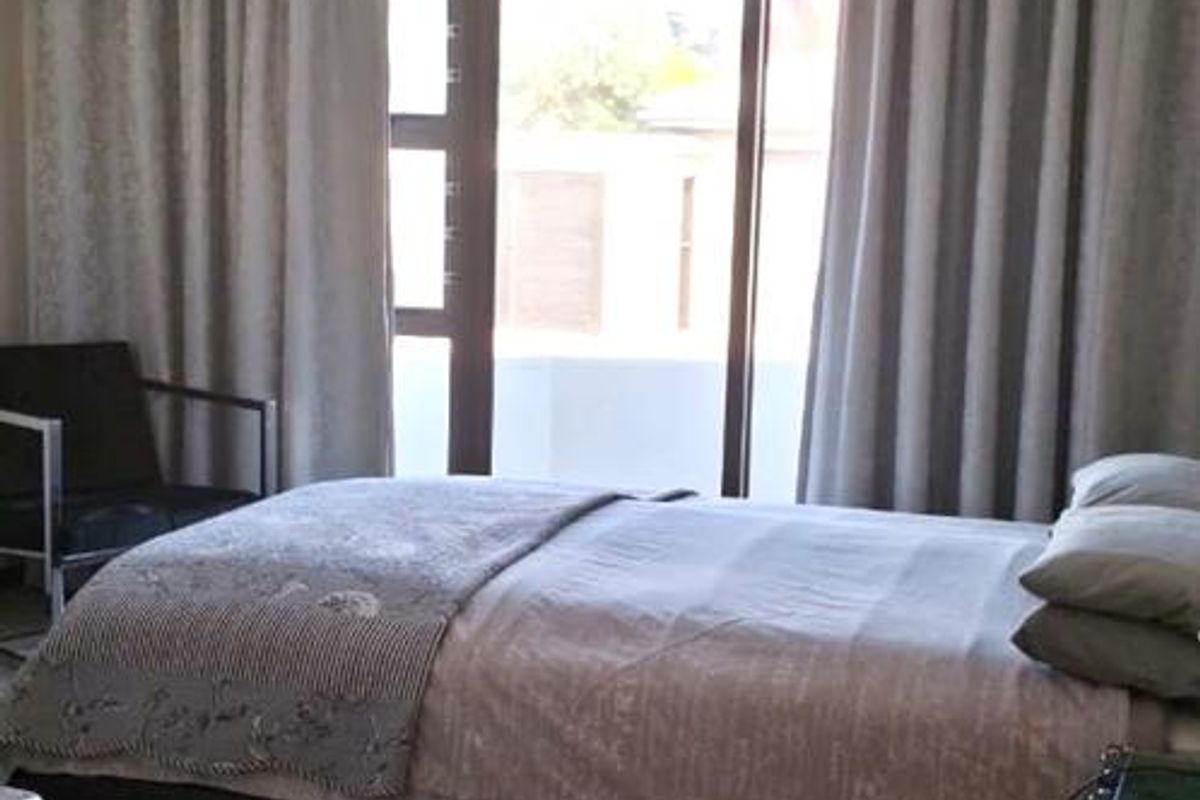 A bedroom featuring tiled flooring and a sliding glass door providing access to an outdoor area, illuminated by a central ceiling light fixture.