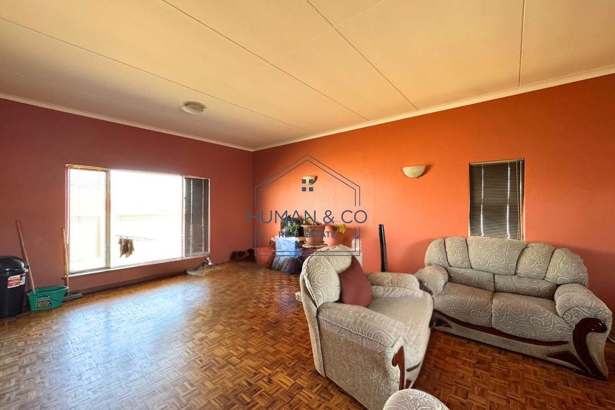 Spacious living room featuring traditional parquet flooring, large windows for natural light, and neutral wall finishes.