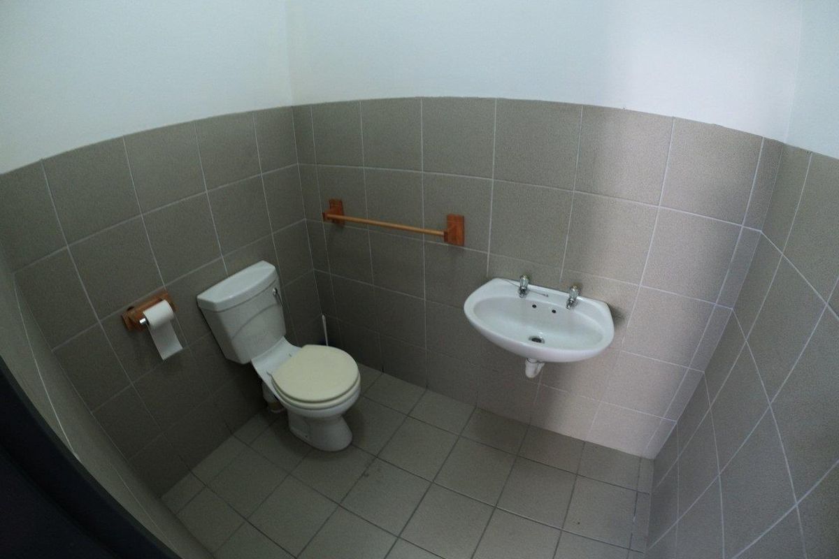 A functional, compact bathroom featuring tiled walls and flooring, equipped with a standard toilet and a wall-mounted basin.