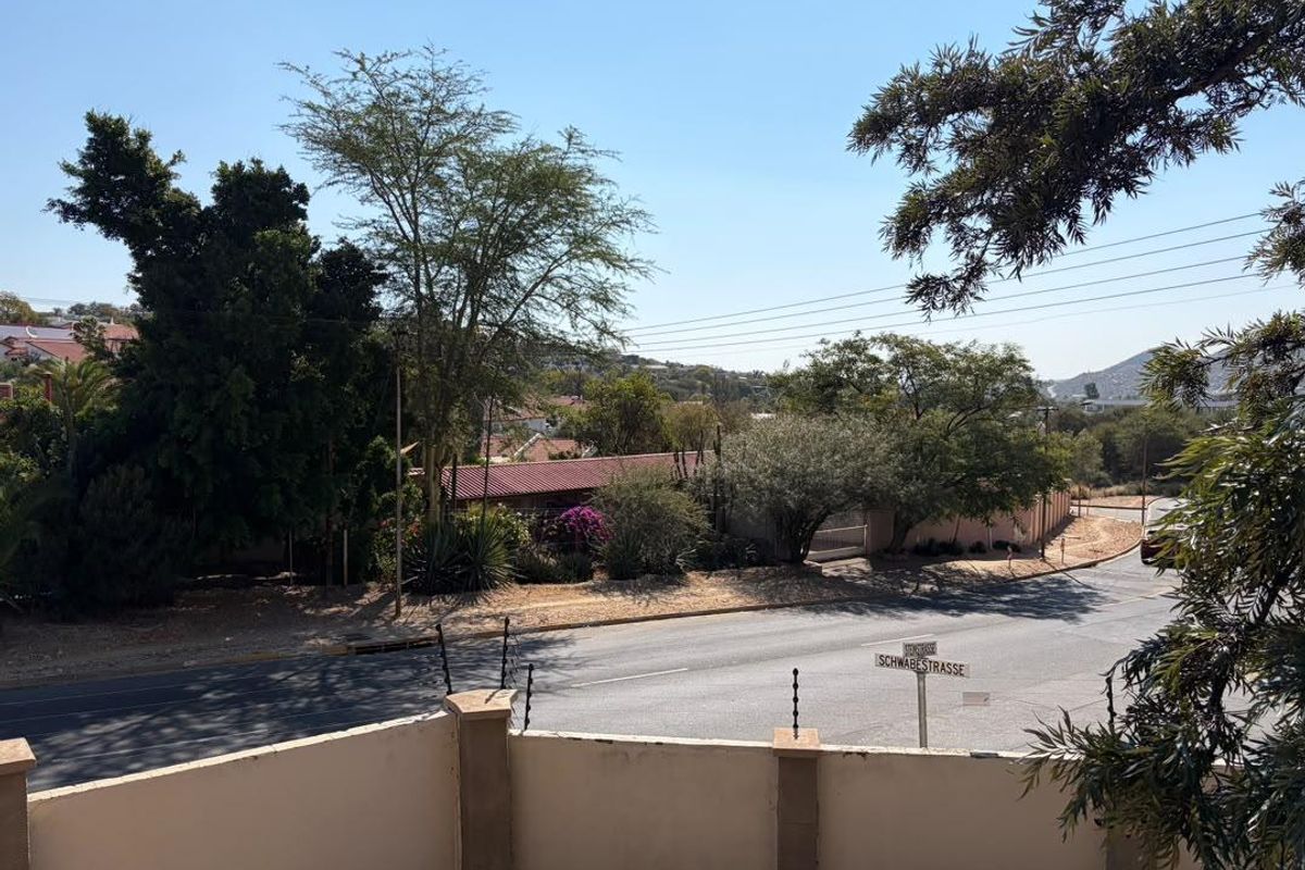 An elevated street view showing the surrounding neighbourhood, local road, and property boundary wall with installed electric fencing.