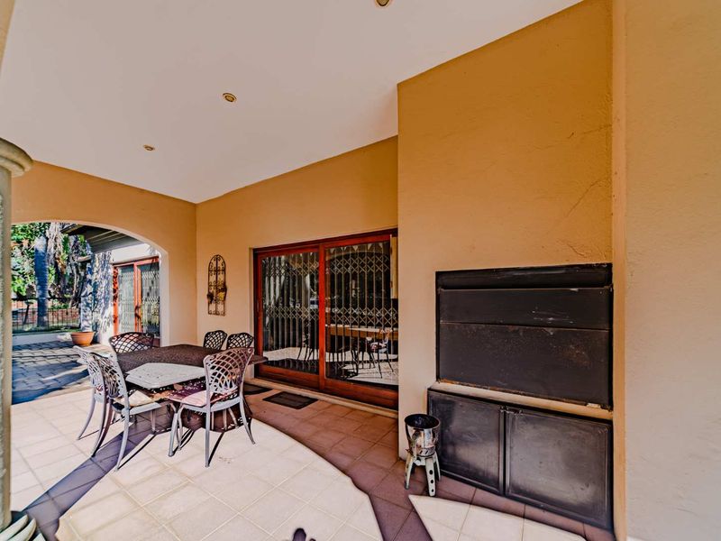 Covered patio area featuring a built-in braai, tiled flooring, and sliding glass door access to the interior living space.
