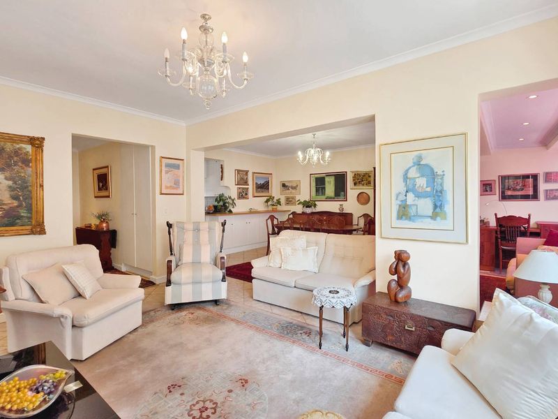 Spacious open-plan living and dining area featuring tiled flooring, classic chandeliers, and integrated cabinetry, offering a versatile layout for comfortable living.