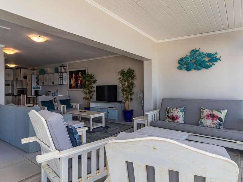 Spacious open-plan living area featuring tiled floors, recessed lighting, and seamless flow to a balcony with glass balustrades.