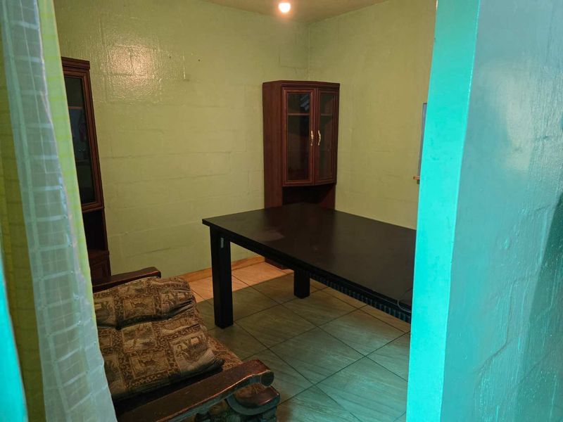 A dining area featuring tiled flooring and painted blockwork walls, offering a functional space ready for modernization and aesthetic updates.