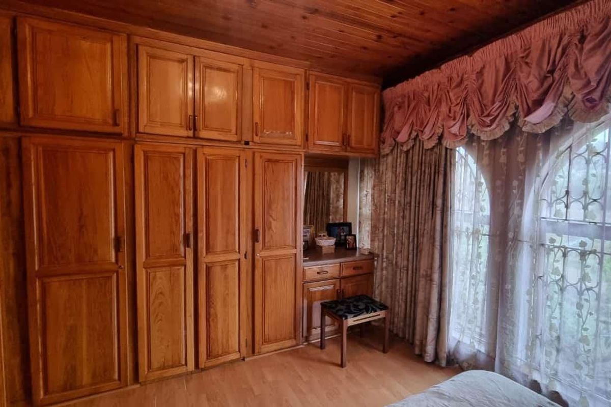 Bedroom featuring extensive built-in wooden cabinetry, a wooden ceiling, and laminate flooring, with security bars installed on the windows.